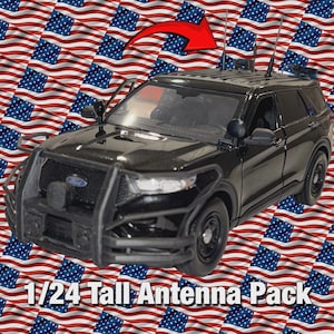 Op de afbeelding: Een zwart 1:24 schaalmodel SUV met een hoog antennepakket. Het model heeft een Ford-embleem en een voorste push bar. De achtergrond heeft een patroon van Amerikaanse vlaggen en een rode pijl wijst naar de antennes. De tekst "1/24 Tall Antenna Pack" staat onderaan.