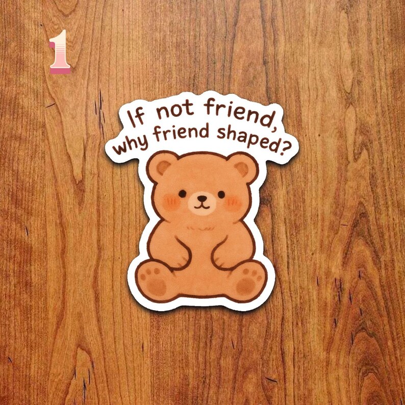 Puede incluir: Una pegatina con forma de oso marr&oacute;n con el texto "If not friend, why friend shaped?" La pegatina tiene un borde blanco y est&aacute; sobre una superficie de madera. El oso tiene un dise&ntilde;o lindo y de dibujos animados.