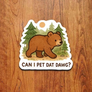 Könnte beinhalten: Aufkleber mit einer Cartoon-Bär-Illustration, vor einer Kulisse aus Bäumen und einer Sonne. Der Text "CAN I PET DAT DAWG?" wird unter dem Bären angezeigt. Der Bär ist braun, und die Bäume sind grün.