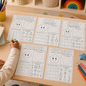 May include: Educational worksheets with geometric shapes, including a triangle, oval, star, diamond, and pentagon. Each worksheet features a shape with a smiling face, tracing lines, and coloring activities. A child is holding a green pencil, ready to complete the worksheets.