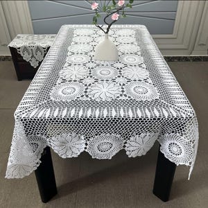 May include: A white ceramic mug with a black handle and the text "But First, Coffee" in a black, handwritten-style font. The mug is on a white surface.