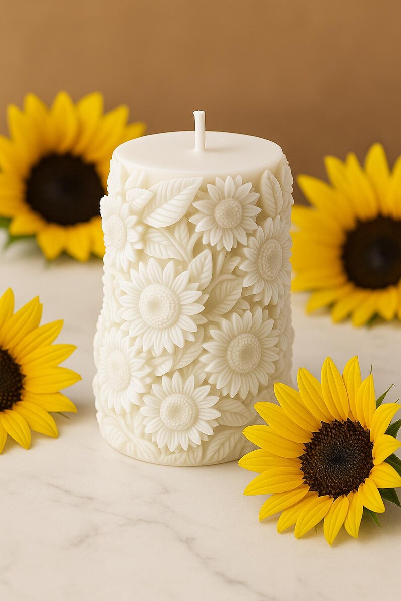 Peut inclure: Une bougie pilier blanche orn&eacute;e d'un motif de tournesol. La bougie est entour&eacute;e de tournesols jaunes avec des centres brun fonc&eacute;. La bougie a une m&egrave;che et est d&eacute;cor&eacute;e de sculptures d&eacute;taill&eacute;es de tournesols et de feuilles.