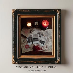 Könnte beinhalten: Ein gerahmter Vintage-Kunstdruck mit einem schwarzen und goldenen verzierten Rahmen. Im Inneren des Rahmens befinden sich Vintage-Karten, Fotografien, eine rote Kerze, eine kleine Kerze und eine kleine Box. Der Text "VINTAGE VANITÉ ART PRINT" und "Vintage Printable Art" befindet sich unten.
