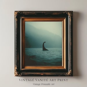 May include: Framed art print featuring a vintage-style image of a creature in a lake, with a dark frame. The artwork has a moody, atmospheric quality, with a dark color palette. The text at the bottom reads "VINTAGE VANITÉ ART PRINT" and "Vintage Printable Art."