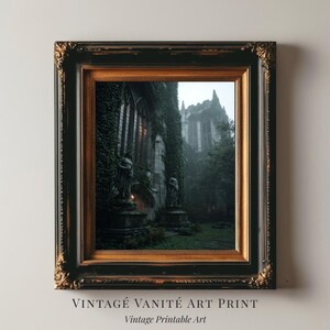 Puede incluir: Una impresión artística enmarcada con estética vintage. La obra representa un edificio gótico cubierto de hiedra, con estatuas y un fondo brumoso. El marco es negro con detalles dorados. El texto en la parte inferior dice "VINTAGE VANITÉ ART PRINT" y "Vintage Printable Art."