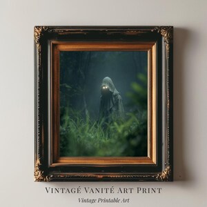 May include: Framed art print featuring a cloaked figure with glowing eyes in a dark forest setting. The artwork is displayed in a black and gold ornate frame. The text "VINTAGE VANITÉ ART PRINT" and "Vintage Printable Art" are at the bottom.