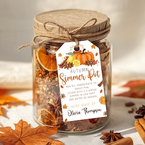 May include: A clear glass jar filled with dried orange slices, cinnamon sticks, and star anise, topped with a tan paper lid and twine. A white tag features autumn illustrations, the text "AUTUMN Simmer Pot", instructions, and "HOME MADE BY: Olivia Thompson".