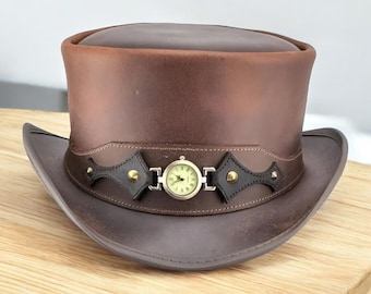 May include: A brown leather top hat with a wide brim. The hat features a decorative band with a small clock in the center and is adorned with gold-colored studs. The hat is a steampunk-inspired accessory.