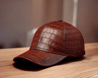 May include: A brown baseball cap with a textured, crocodile-effect pattern. The cap features a curved peak and a small button on top. The hat is made of a shiny, leather-like material and rests on a wooden surface.