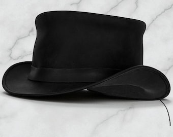 Peut inclure: Un chapeau haut de forme noir avec un large bord et une bande noire autour de la couronne. Le chapeau est fait d'un matériau lisse et repose sur une surface en marbre blanc. Ce chapeau classique est adapté aux événements formels.