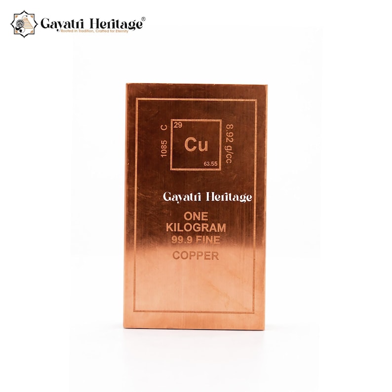 May include: A copper bar with the Gayatri Heritage logo. The bar features the element symbol Cu, atomic number 29, and the text "ONE KILOGRAM 99.9 FINE COPPER". The bar is a reddish-brown color.