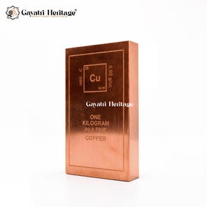 May include: A copper bar with the text "ONE KILOGRAM 99.9 FINE COPPER" and the chemical symbol "Cu". The bar has the Gayatri Heritage logo and is displayed on a white background.