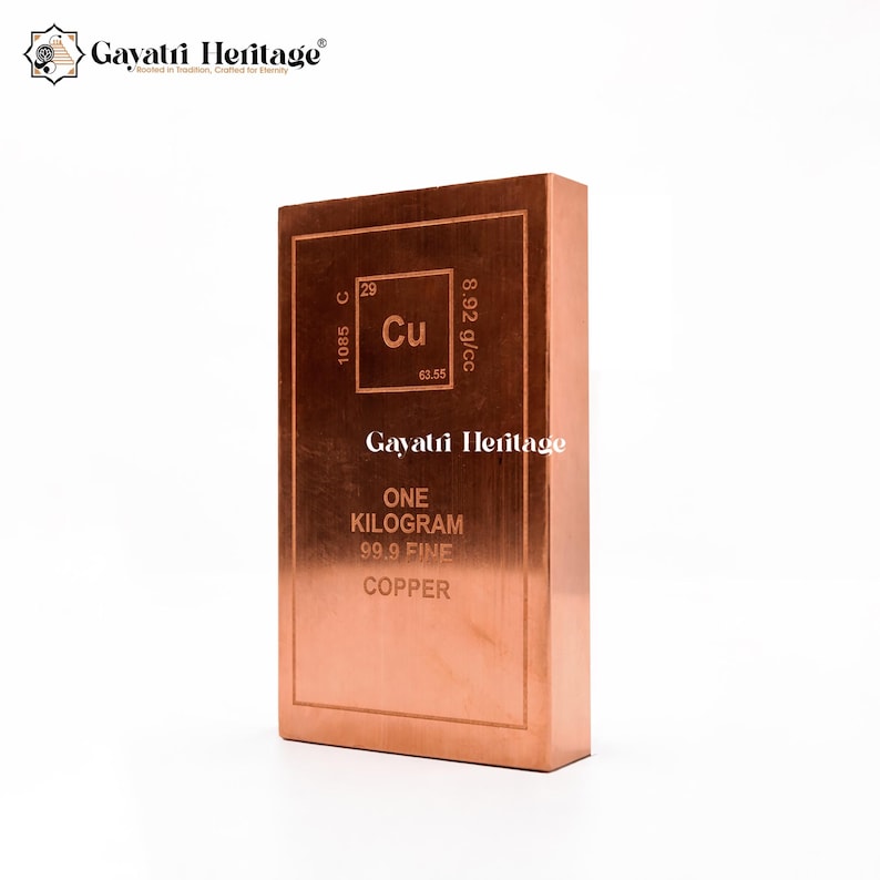 May include: A copper bar with the text "ONE KILOGRAM 99.9 FINE COPPER" and the chemical symbol "Cu". The bar has the Gayatri Heritage logo and is displayed on a white background.