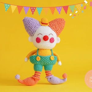 May include: A handmade crochet clown doll with a white face, red cheeks, and a small hat. The clown wears a yellow shirt, green dungarees, and colourful shoes. A festive banner hangs above the doll against a yellow background.