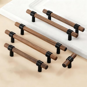 Könnte beinhalten: Schrankgriffe mit modernem Design. Die Griffe haben einen braunen Mittelteil in Holzoptik und schwarze Metallakzente. Die Hardware ist für eine einfache Installation konzipiert und verleiht jedem Schrank einen Hauch von Eleganz.