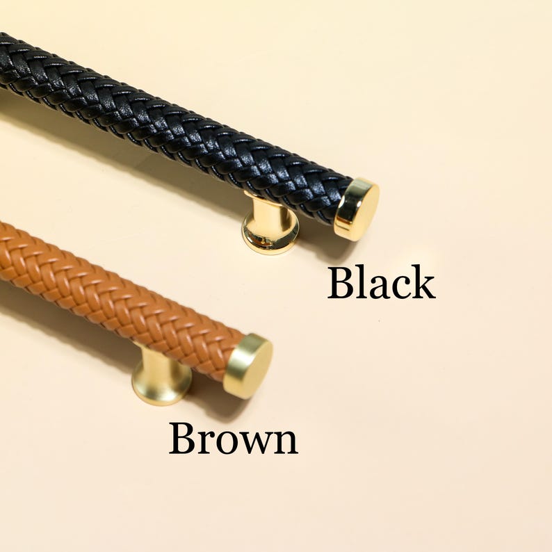 Puede incluir: Dos tiradores de armario, uno negro y otro marr&oacute;n, con un dise&ntilde;o de cuero trenzado. Los tiradores tienen herrajes de montaje y tapas de extremo doradas. La palabra "Black" est&aacute; impresa junto al tirador negro, y la palabra "Brown" junto al marr&oacute;n.