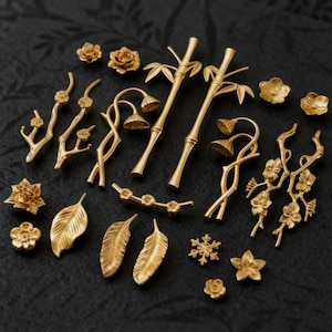 Peut inclure: Une collection de quincaillerie décorative dorée, comprenant des poignées de tiroir, des boutons et des accents décoratifs. La quincaillerie présente des motifs floraux, de feuilles, de bambou et de branches. La quincaillerie est présentée sur un fond sombre.