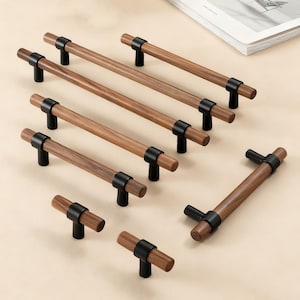 Op de afbeelding: Een verzameling houten kastgrepen met zwarte metalen accenten. De grepen hebben een cilindrische houten handgreep en zijn bevestigd aan een zwarte metalen basis. Het hout heeft een natuurlijke nerf en een warme bruine kleur. Meubelbeslag.