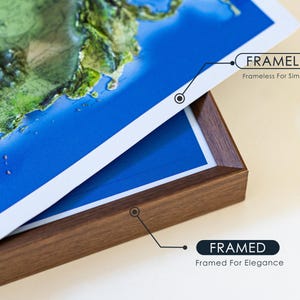 Op de afbeelding: Een gedetailleerde kaartafdruk met een blauwe oceaan en groene landmassa's. De afdruk is verkrijgbaar in zowel frameloze als ingelijste opties. De ingelijste versie heeft een donkerbruine houten lijst. De tekst op de afbeelding luidt "FRAMED" en "FRAMELESS".