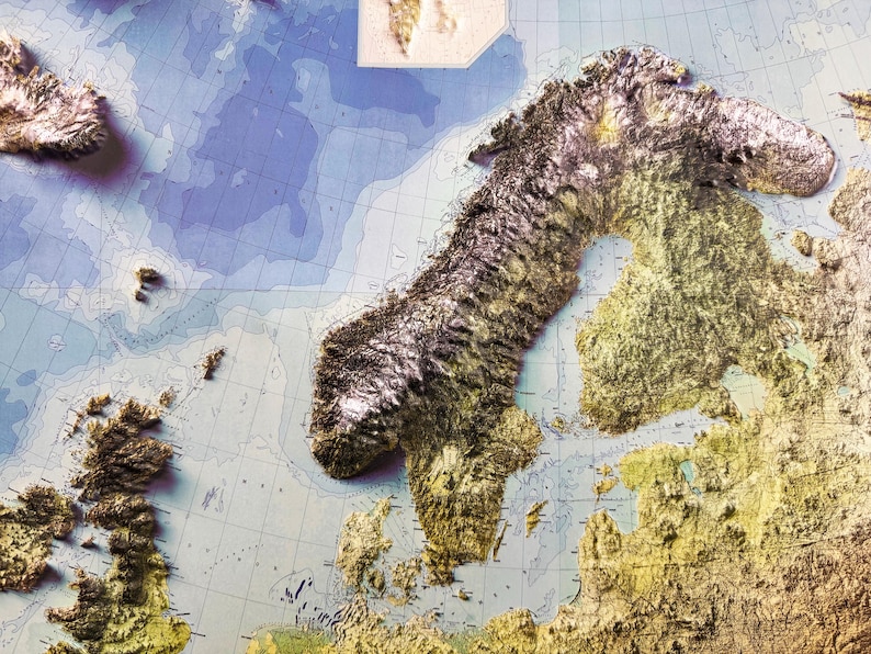 Op de afbeelding: Een gedetailleerde reli&euml;fkaart van Noord-Europa, met de Scandinavische schiereiland en de omliggende gebieden. De kaart toont getextureerde, verhoogde landmassa's in bruin- en goudtinten, tegen een blauw-witte oceaanachtergrond. Rasterlijnen en labels zijn zichtbaar.