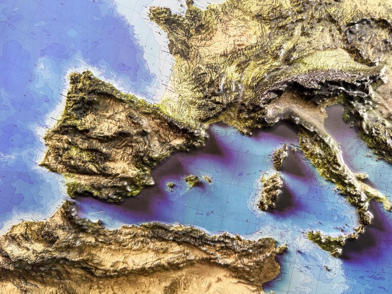 Op de afbeelding: Een 3D-reli&euml;fkaart van Europa, met de nadruk op het Iberisch schiereiland en Itali&euml;. De kaart toont gedetailleerde topografie in tinten bruin, groen en beige, met blauw dat de zee voorstelt. De kaart is een visuele weergave van de hoogte van het land.