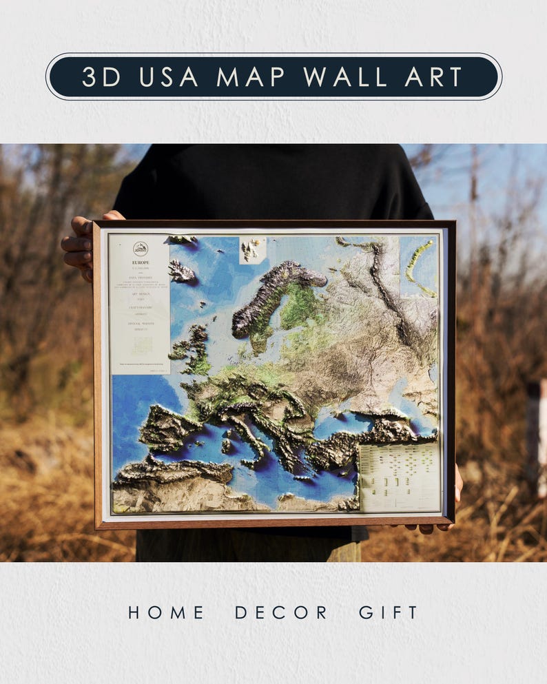 Op de afbeelding: Een ingelijste 3D-kaart van Europa met een houten frame. De kaart toont gedetailleerd reli&euml;f, met blauwe oceanen en verschillende landhoogtes. De tekst "3D USA MAP WALL ART" staat bovenaan. De woorden "HOME DECOR GIFT" staan onderaan.