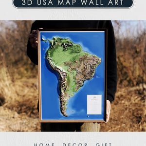 Peut inclure: Une carte 3D encadrée de l'Amérique du Sud, avec une représentation topographique détaillée en nuances de vert, de brun et de bleu. L'œuvre est présentée sur un fond extérieur naturel. Le texte en haut indique "3D USA MAP WALL ART" et en bas "HOME DECOR GIFT".