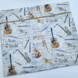 May include: A flat, rectangular zippered pouch featuring a cream-colored fabric with a musical theme. The print displays various instruments like guitars, saxophones, and violins over sheet music, with the text "Where words fail, music speaks."