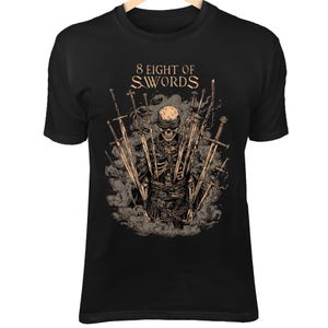 Puede incluir: Camiseta negra con un diseño detallado de un esqueleto rodeado de espadas y humo. El texto "8 EIGHT OF SWORDS" está impreso arriba. El diseño utiliza tonos beige y gris.