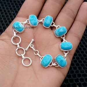 May include: A silver bracelet featuring rectangular, light blue gemstones. The bracelet is connected by silver links and has a toggle clasp. The text "ShriBalajiJewlry" is visible on the image.