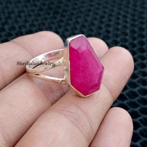 May include: A sterling silver ring featuring a large, faceted, magenta-colored gemstone. The ring has a split shank design and the text "ShriBalajiJewlry" is visible on the band.
