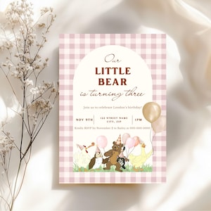 May include: A pink and white gingham patterned invitation with the text "Our LITTLE BEAR is turning three." The invitation includes illustrations of animals and balloons. The date, time, and RSVP information are also included.