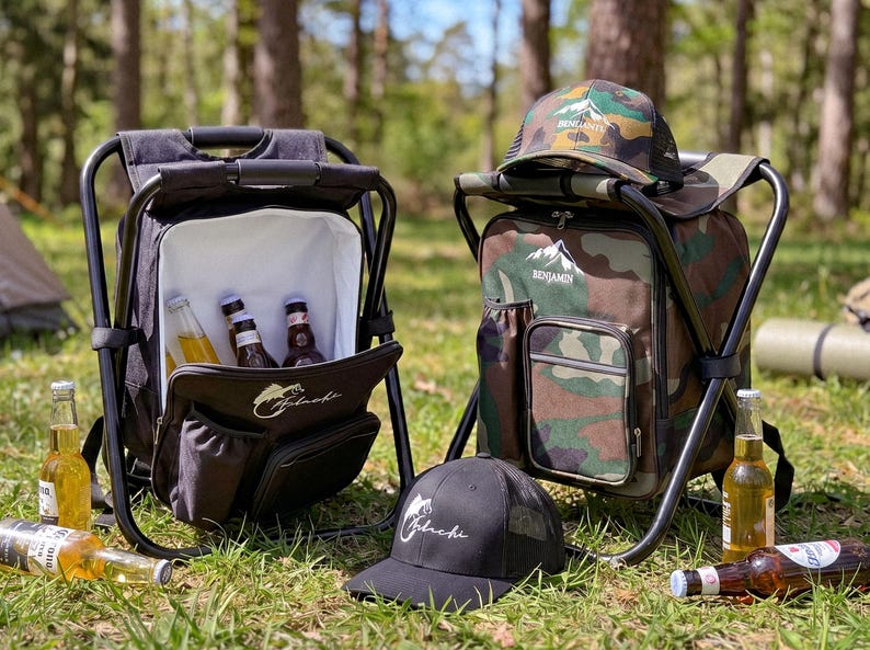 May include: Two portable folding stool backpacks, one solid black and one camouflage print, each featuring a white interior cooler compartment. The black bag displays a fish logo, while the camouflage bag features a mountain logo and matching cap.