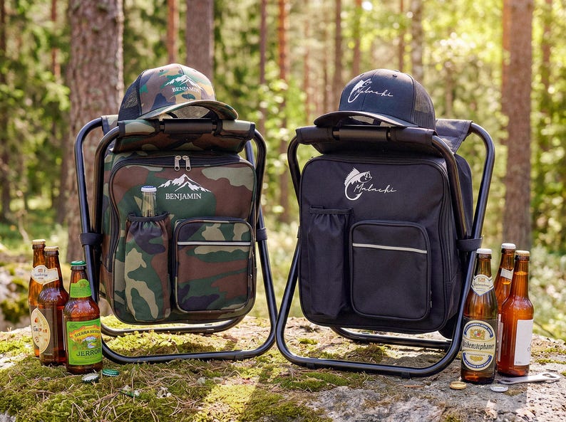 May include: Two portable folding chair backpacks, one in camouflage print with the name Benjamin and a mountain graphic, and one in solid black with the name Malachi and a fish graphic. Each includes a matching baseball cap and glass beer bottles.