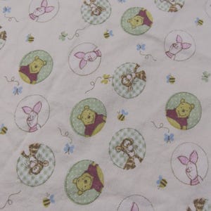 May include: Cream fabric featuring a repeating pattern of Winnie the Pooh characters in green circles. The design includes Pooh Bear, Piglet, Tigger, and bees, with small blue butterflies and floral accents scattered throughout.