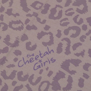May include: Close-up of a fabric with a lavender cheetah print pattern. The text "the Cheetah Girls" is printed in a matching lavender color. The fabric has a soft, textured appearance.