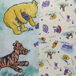 May include: Two panels of fabric featuring Winnie the Pooh characters. One panel has a large yellow Pooh bear and a tiger. The other panel has a repeating pattern of Pooh, Piglet, and Tigger with seasonal words.