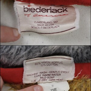 May include: A white fabric label featuring red text stating Biederlack of America, Cumberland, MD, Made in USA. The reverse side details 85% virgin acrylic and 15% cotton, care instructions, and a separate tag for The Walt Disney Company.