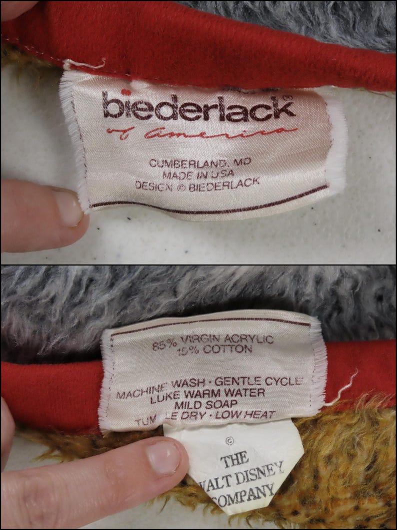May include: A white fabric label featuring red text stating Biederlack of America, Cumberland, MD, Made in USA. The reverse side details 85% virgin acrylic and 15% cotton, care instructions, and a separate tag for The Walt Disney Company.