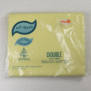 May include: A double flat sheet in a pale yellow color, packaged in clear plastic. The sheet has text that reads "NO IRON" and "SELECTED SECONDS". The packaging also indicates the sheet is for a 54 x 75 inch mattress and is 81 x 96 inches when finished.