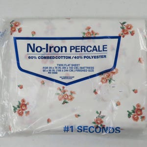 May include: A twin flat sheet in a plastic package. The sheet is white with a floral pattern in shades of peach and green. The packaging includes text that reads "No-Iron Percale" and measurements for a 99 x 193 cm mattress.