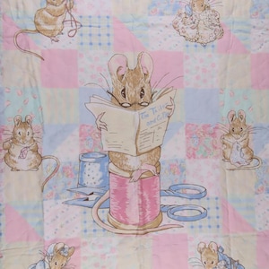 May include: A pastel patchwork quilt with illustrations of mice. The mice are depicted sewing and reading a newspaper titled "The Tailor and Cutter". The quilt's design incorporates pink, blue, and yellow squares, creating a soft, inviting aesthetic.