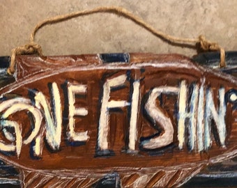 A brown-colored handmade gone fishin' sign,  many unique features to this sign, different type of lettering, Rope-hung, Whimsical edges