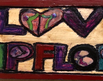 A small wood relief carving - "I Lo(heart)ve Flip Flops" - Flip-Flop related - unique letters with images of flip flops on a small plank -