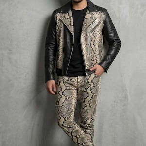 May include: A black leather jacket with snake print panels, paired with matching snake print pants. The jacket has a classic biker style with a zipper closure. The outfit is completed with brown boots, creating a bold, edgy look.