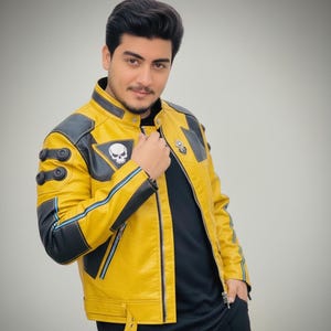 May include: A yellow and black leather jacket with a skull patch on the chest. The jacket has blue stripes, black accents, and a zipper closure. The person is wearing a black shirt.