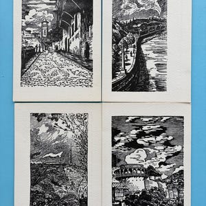 Pode incluir: Quatro gravuras em linóleo a preto e branco que retratam cenas arquitetónicas e paisagísticas. As gravuras apresentam ruas de calçada, edifícios, um rio e uma torre. A obra de arte está sobre um fundo branco.