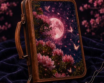 May include: A brown leather-like zippered case featuring a rectangular front panel with a printed scene of a large pink moon, blooming pink flowers, a hummingbird, and butterflies against a dark night sky, complete with a side carrying handle.