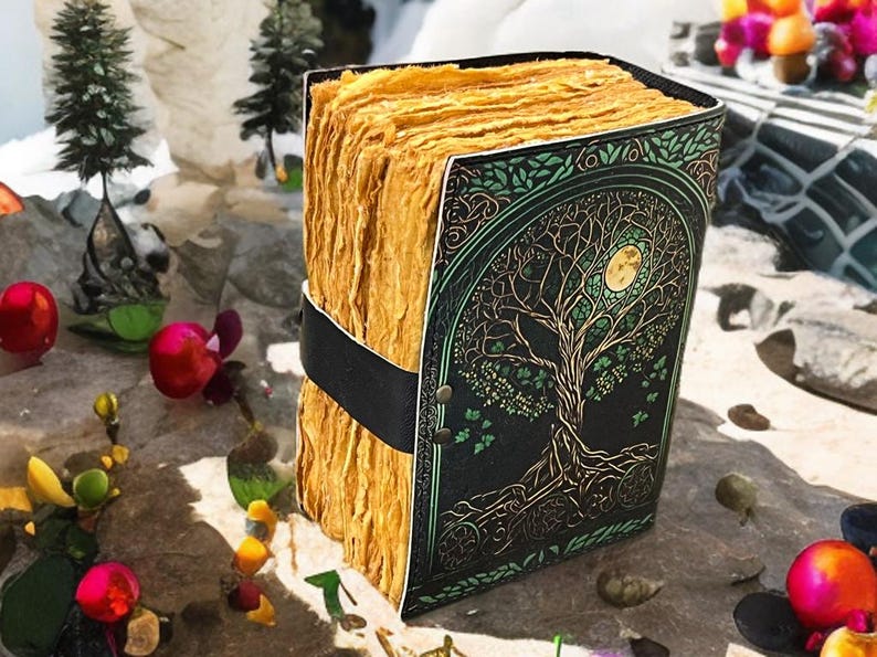 Puede incluir: Un diario hecho a mano con una cubierta negra con un dise&ntilde;o de &aacute;rbol de la vida en dorado y verde. Las p&aacute;ginas son de color dorado texturizado, encuadernadas con una correa negra. Un art&iacute;culo art&iacute;stico &uacute;nico.