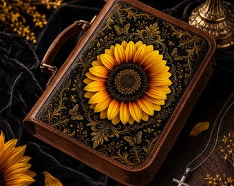 May include: A rectangular brown leather-like case with a handle, featuring a large yellow sunflower centered on a black background. The design includes intricate gold filigree patterns and small butterfly motifs surrounding the sunflower.